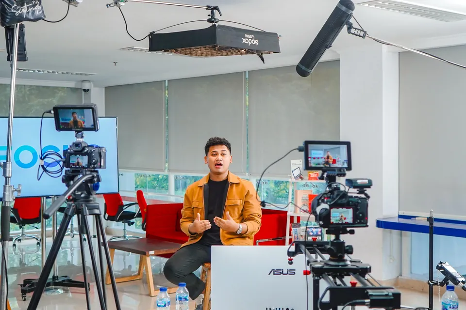 A presenter filmed in the studio with two cameras and production lights